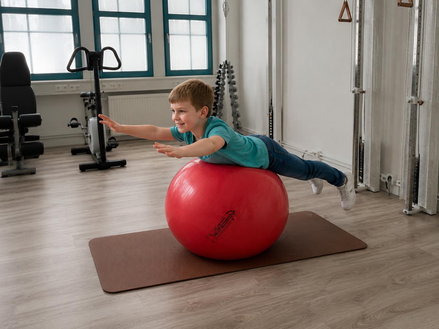 Kind beim Gleichgewichtstraining auf dem Gymnastikball in der Praxis Varupa